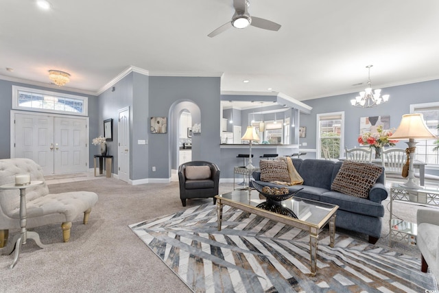 living room with a wealth of natural light, crown molding, carpet flooring, and ceiling fan with notable chandelier