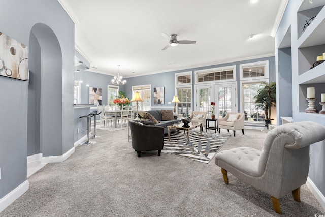 carpeted living room featuring french doors, ornamental molding, and ceiling fan with notable chandelier