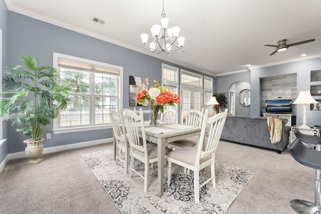 carpeted dining area featuring crown molding and ceiling fan with notable chandelier