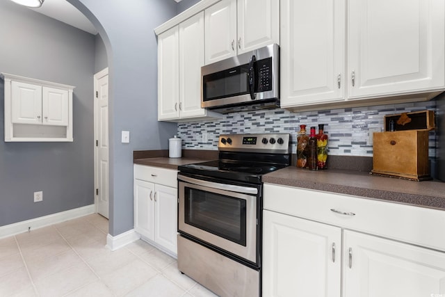 kitchen featuring decorative backsplash, white cabinets, stainless steel appliances, and light tile patterned flooring