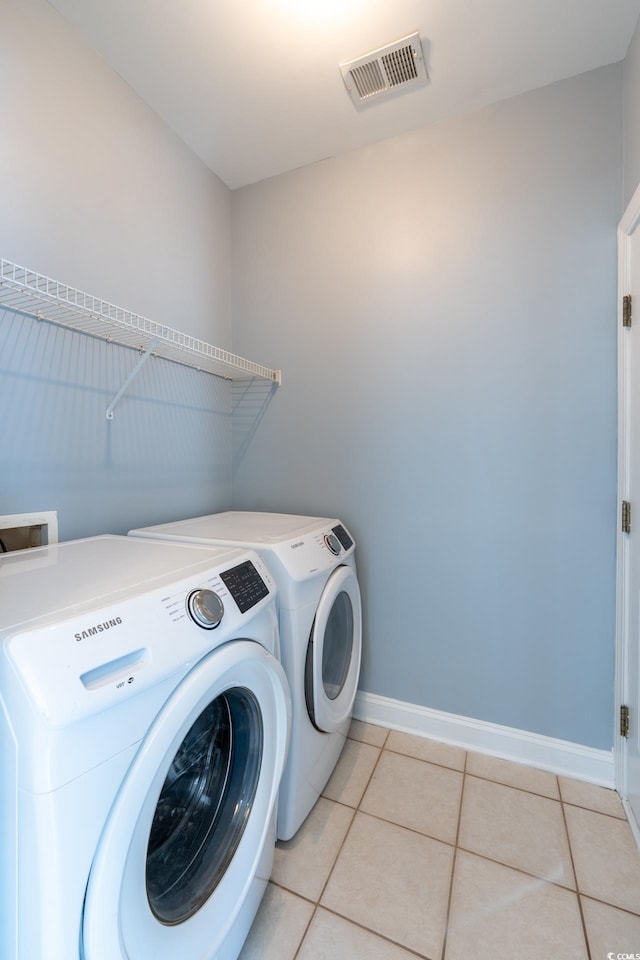 laundry area with washer and dryer and light tile patterned floors