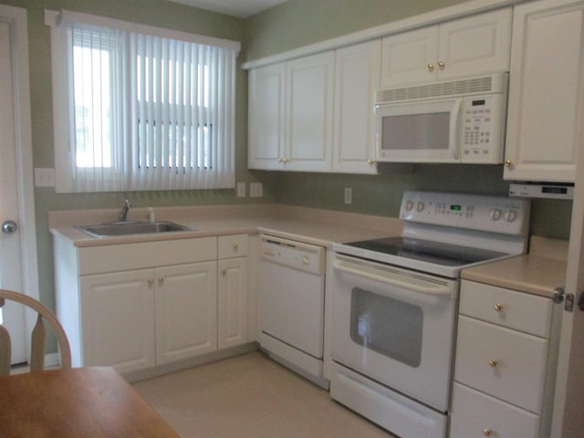 kitchen with white appliances, white cabinetry, and sink