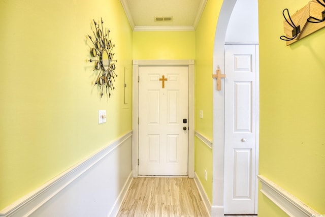 doorway with crown molding and light hardwood / wood-style flooring