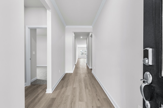 hallway with light wood-type flooring and ornamental molding