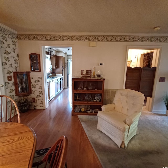 living room with crown molding, wood-type flooring, and a textured ceiling