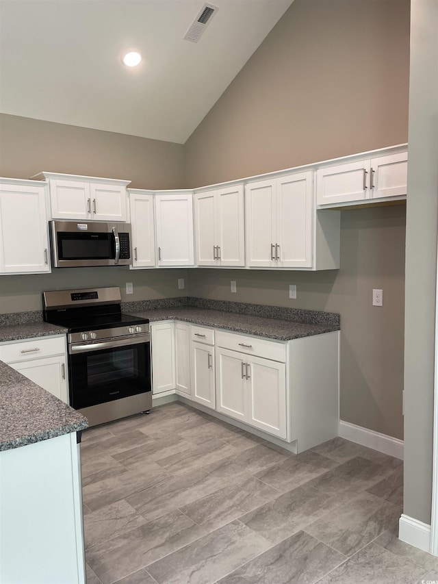 kitchen with white cabinets, high vaulted ceiling, appliances with stainless steel finishes, and dark stone counters