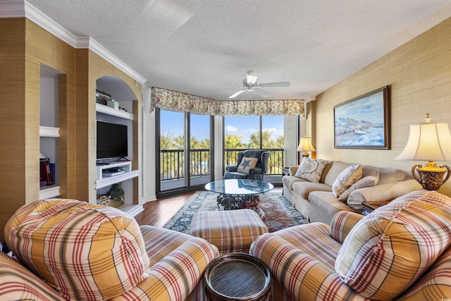 living room featuring crown molding, a textured ceiling, built in shelves, hardwood / wood-style floors, and ceiling fan