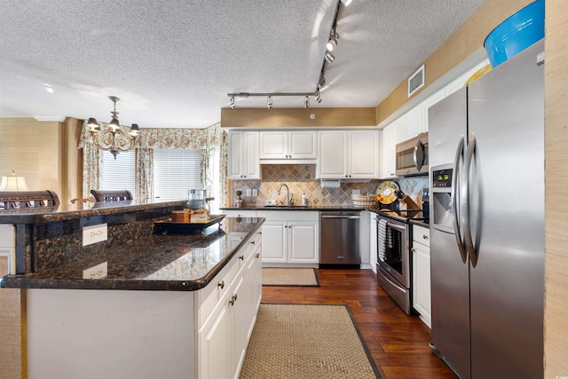 kitchen with stainless steel appliances, dark wood-type flooring, track lighting, sink, and white cabinets