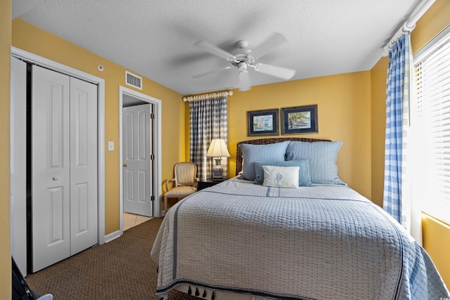 carpeted bedroom with a closet, ceiling fan, and a textured ceiling