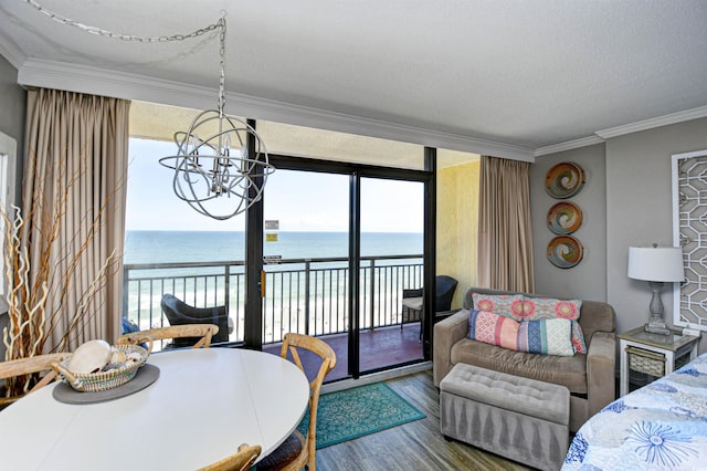 dining space with wood-type flooring, ornamental molding, a notable chandelier, a water view, and expansive windows