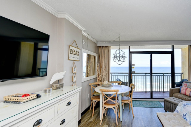 dining space featuring dark hardwood / wood-style flooring, crown molding, a water view, and a notable chandelier