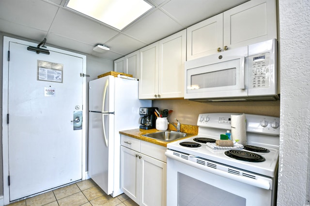 kitchen featuring a drop ceiling, sink, white appliances, white cabinetry, and light tile patterned flooring