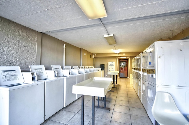 laundry area with stacked washer / dryer, washing machine and dryer, and light tile patterned flooring