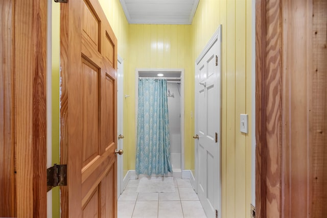 hallway featuring wooden walls and light tile patterned floors