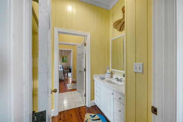 bathroom with vanity, crown molding, wooden walls, and hardwood / wood-style floors