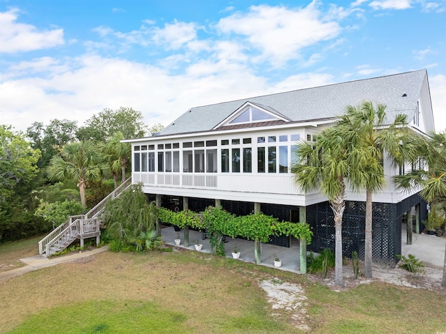 back of house featuring a sunroom and a lawn