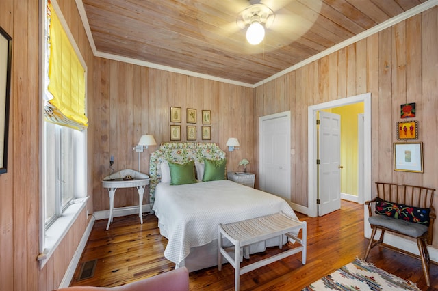 bedroom with wood-type flooring, crown molding, wooden walls, and wooden ceiling