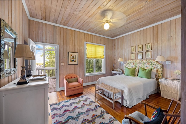 bedroom featuring hardwood / wood-style flooring, wood walls, crown molding, and multiple windows