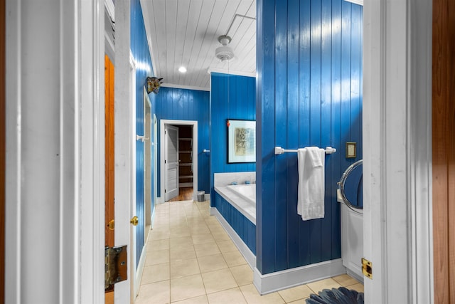 bathroom featuring tile patterned flooring, wood walls, and a tub to relax in