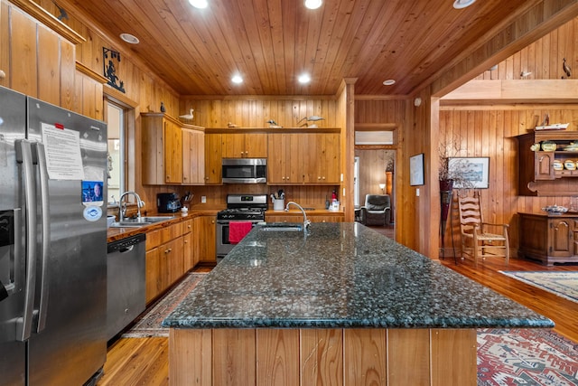 kitchen with wood walls, appliances with stainless steel finishes, light hardwood / wood-style flooring, and sink