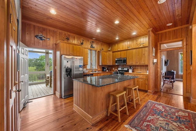 kitchen featuring wooden walls, a center island, light hardwood / wood-style flooring, and appliances with stainless steel finishes