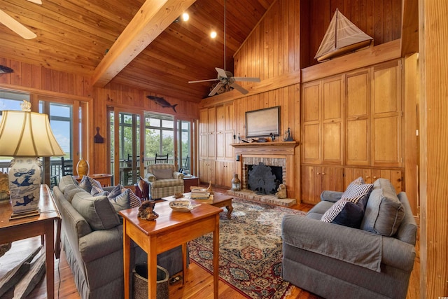 living room with light hardwood / wood-style floors, wood walls, a brick fireplace, and ceiling fan