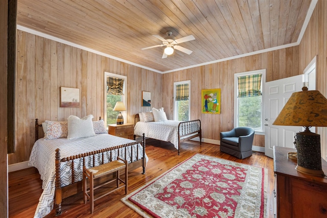 bedroom with hardwood / wood-style flooring, ceiling fan, wooden walls, ornamental molding, and wood ceiling