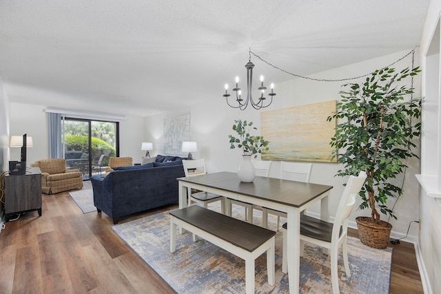 dining room featuring a notable chandelier, hardwood / wood-style flooring, and a textured ceiling