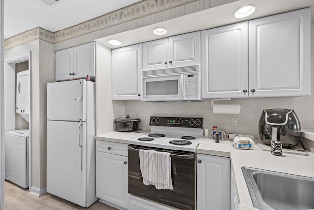 kitchen with white cabinetry, stacked washer / drying machine, white appliances, and sink