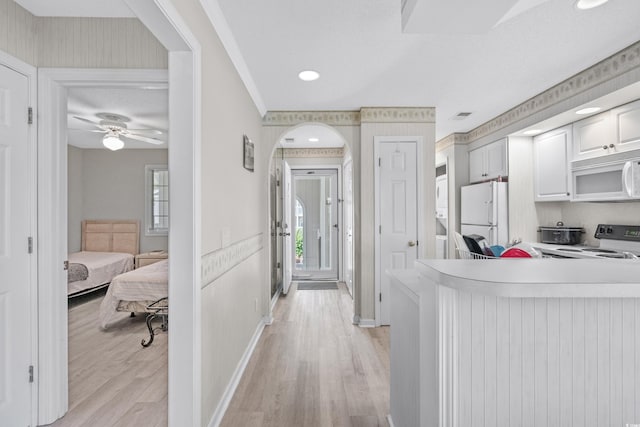 kitchen with white cabinets, light wood-type flooring, white appliances, and ceiling fan