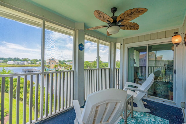 sunroom / solarium featuring ceiling fan and a water view