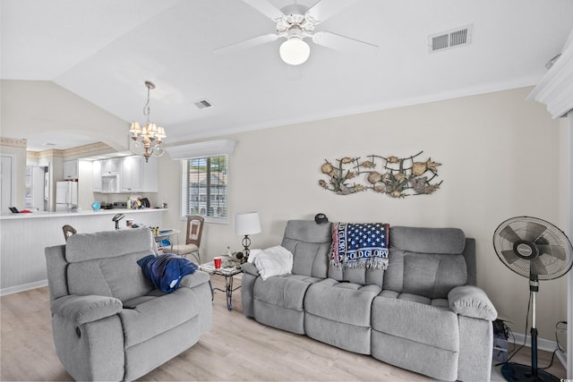 living room featuring ceiling fan with notable chandelier, light wood-type flooring, and vaulted ceiling