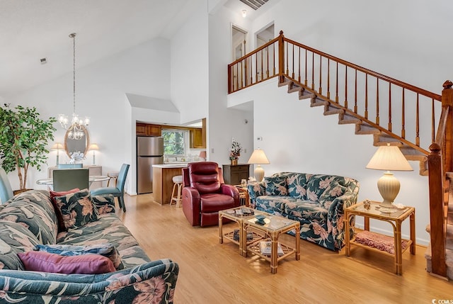 living room featuring light hardwood / wood-style floors, high vaulted ceiling, and a chandelier