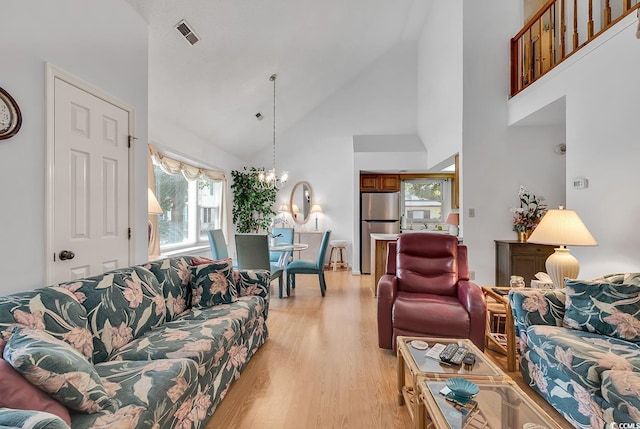 living room featuring a chandelier, light wood-type flooring, and high vaulted ceiling