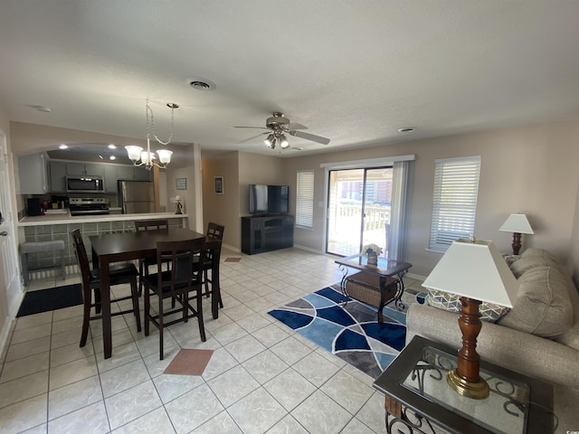 living room with light tile patterned floors and ceiling fan with notable chandelier