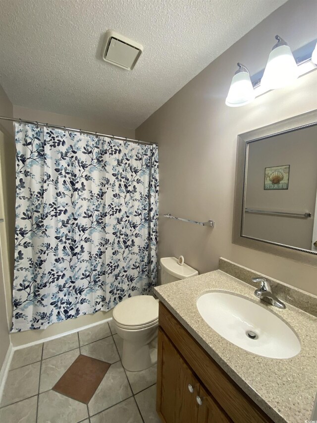 bathroom featuring walk in shower, a textured ceiling, vanity, tile patterned flooring, and toilet