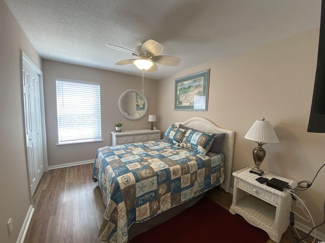 bedroom featuring ceiling fan, dark wood-type flooring, a textured ceiling, and a closet