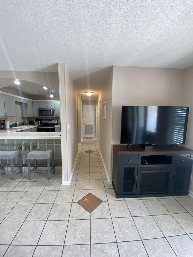 unfurnished living room featuring light tile patterned floors and a textured ceiling