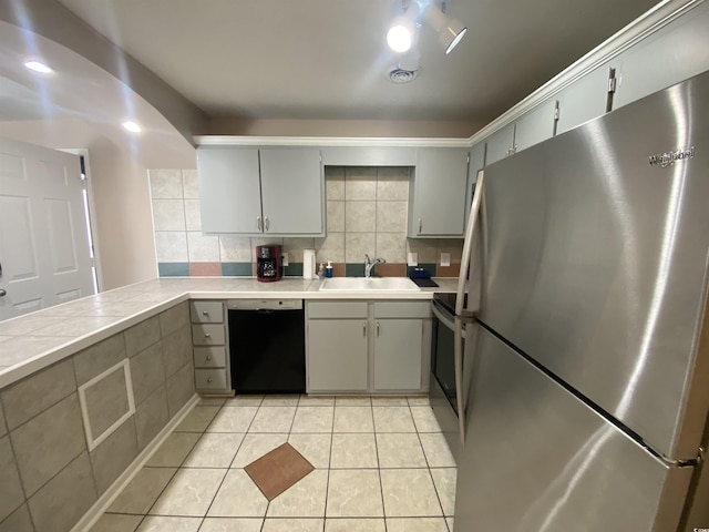 kitchen featuring decorative backsplash, light tile patterned floors, stainless steel appliances, and sink