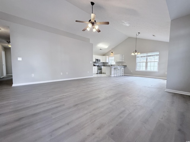 unfurnished living room with hardwood / wood-style floors, high vaulted ceiling, and ceiling fan