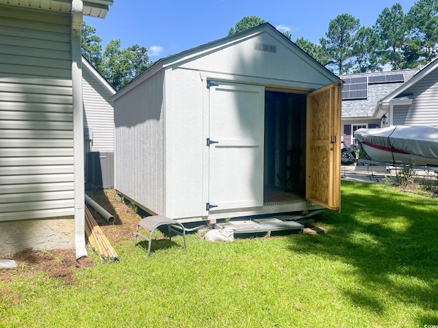 view of outdoor structure featuring a yard and central AC unit