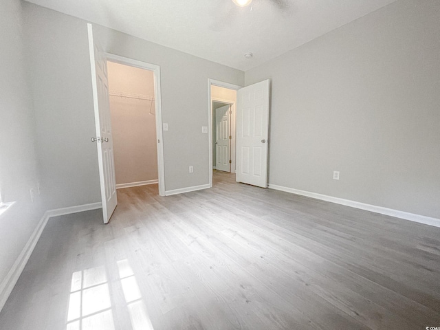 unfurnished bedroom featuring a closet, a spacious closet, and light hardwood / wood-style flooring