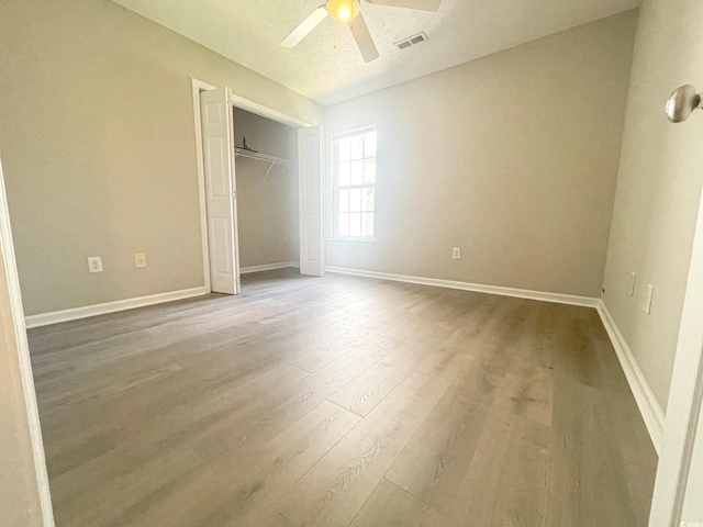 unfurnished bedroom with wood-type flooring, ceiling fan, and a closet