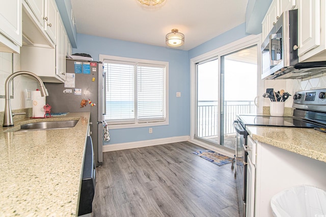 5800 N Ocean Blvd Unit 705, North Myrtle Beach, SC 29582 - kitchen with electric range oven, stainless steel microwave, wood finished floors, backsplash, and white cabinets