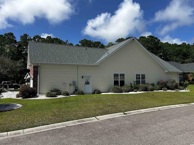 ranch-style house featuring roof with shingles and a front yard