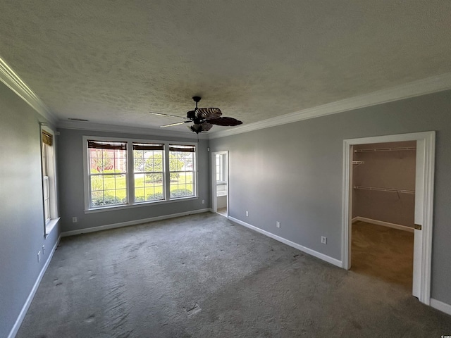 carpeted spare room featuring a textured ceiling, baseboards, a ceiling fan, and crown molding