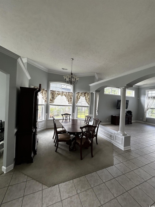 dining room featuring a healthy amount of sunlight, light tile patterned flooring, decorative columns, and an inviting chandelier