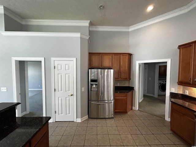 kitchen featuring tasteful backsplash, washer / clothes dryer, crown molding, and stainless steel fridge with ice dispenser