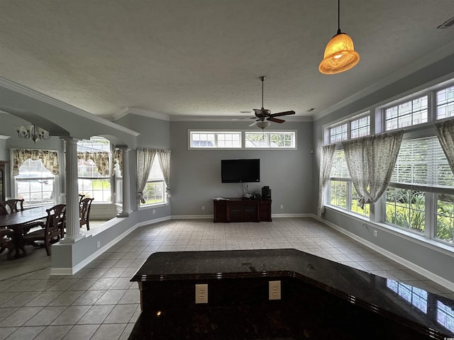 unfurnished living room with arched walkways, ornate columns, ornamental molding, tile patterned flooring, and baseboards