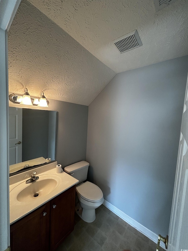 bathroom featuring a textured ceiling, vanity, visible vents, vaulted ceiling, and baseboards